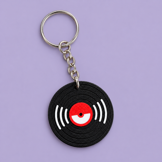 Black vinyl record NFC keychain with a red centre, white groove accents and a silver keyring on a lavender background.