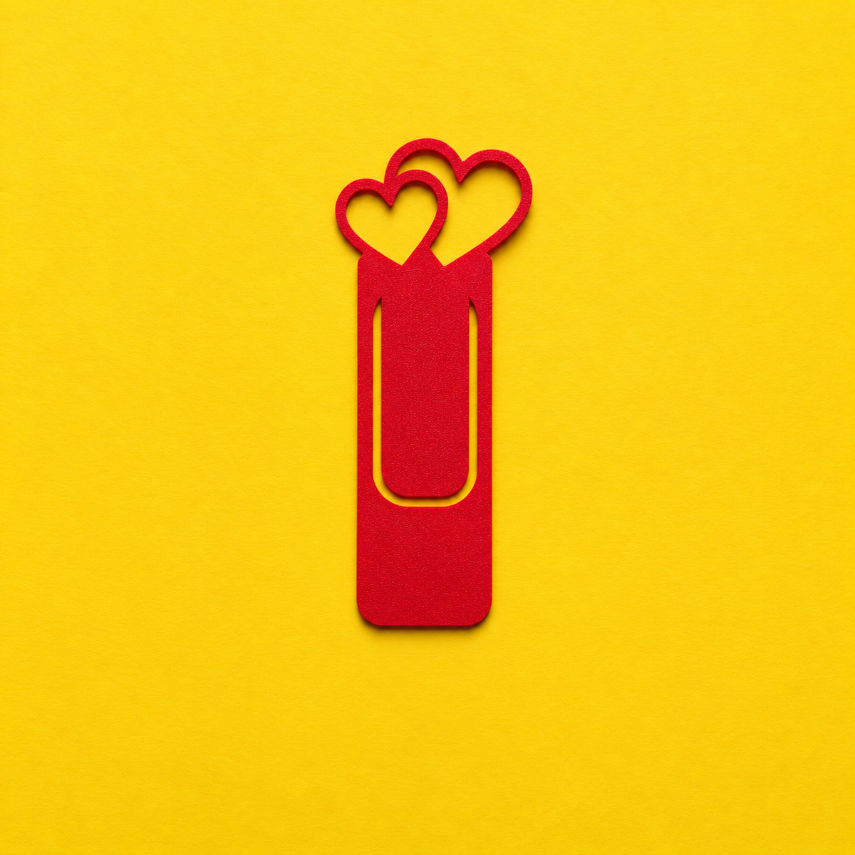 Red 3D printed bookmark with two heart outlines and a slim page clip on a yellow background