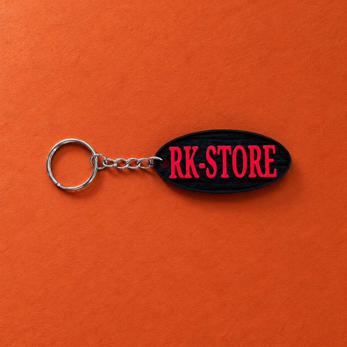 Schwarzer RK-STORE-Schlüsselanhänger mit roter Schrift auf Terrakotta