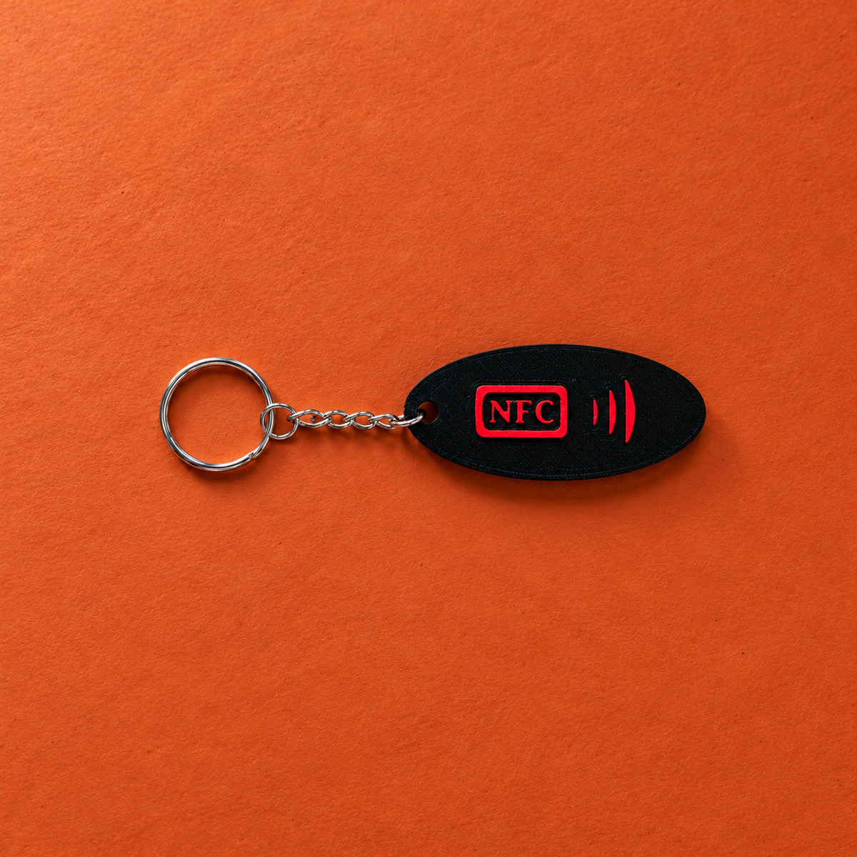 Rückseite eines schwarzen Schlüsselanhängers mit rotem NFC-Symbol auf Terrakotta