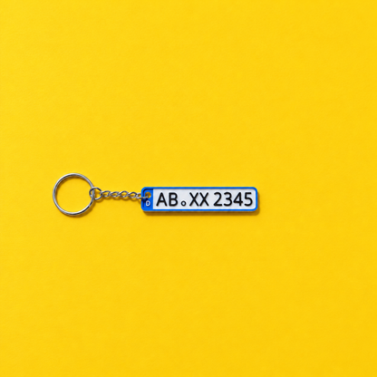 Miniature license plate keychain with black lettering and blue border on a yellow background