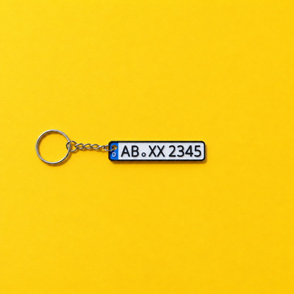 Miniature license plate keychain with black lettering and black border on a yellow background
