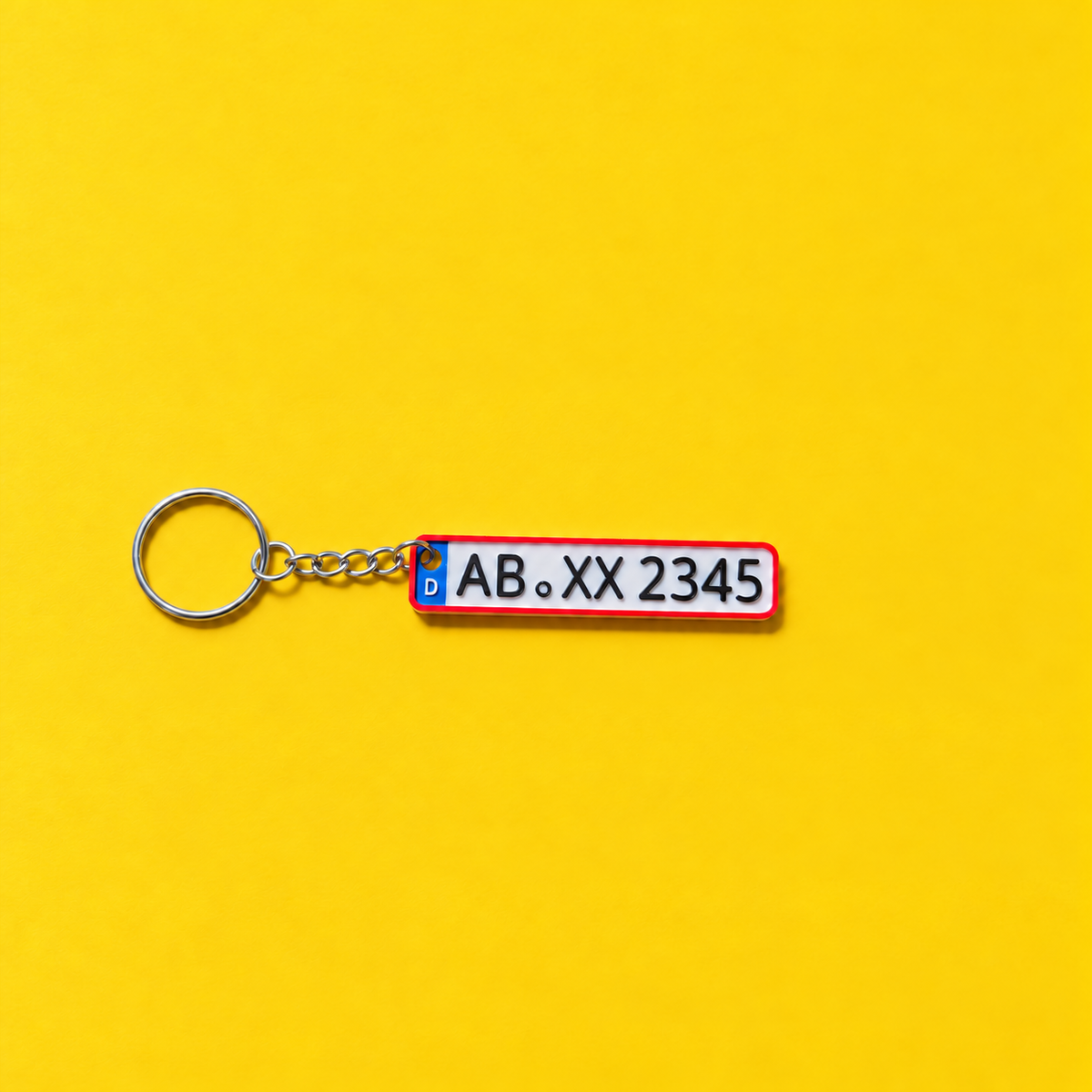 Miniature license plate keychain with black lettering and red border on a yellow background