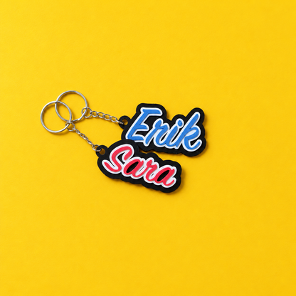Sara and Erik 3D printed name keychains with white outlines and black backing