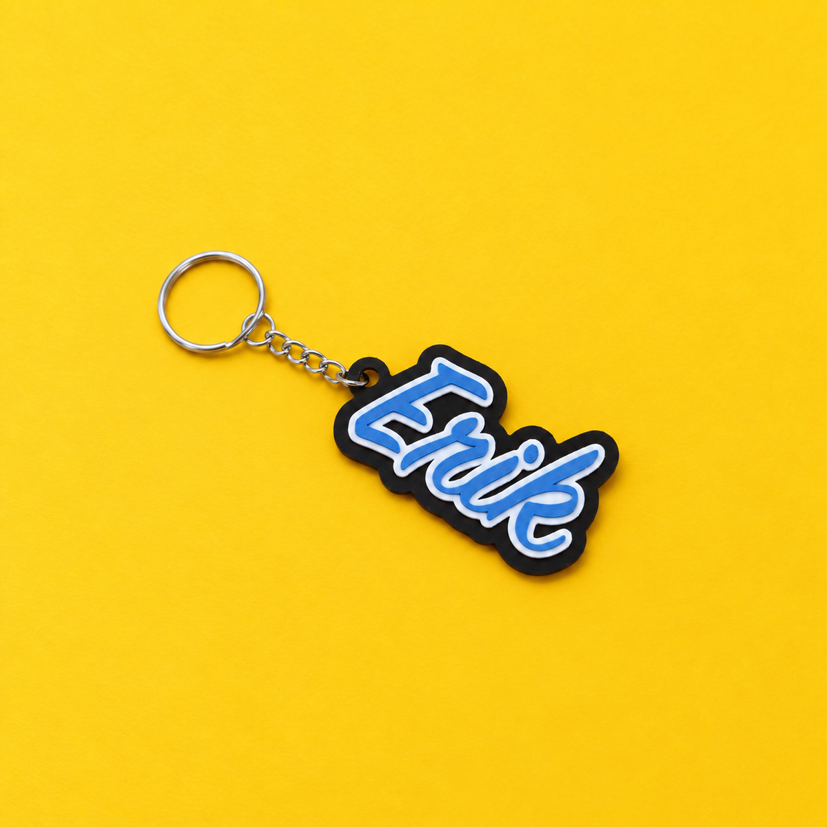 Blue Erik personalized name keychain with silver ring on a yellow background
