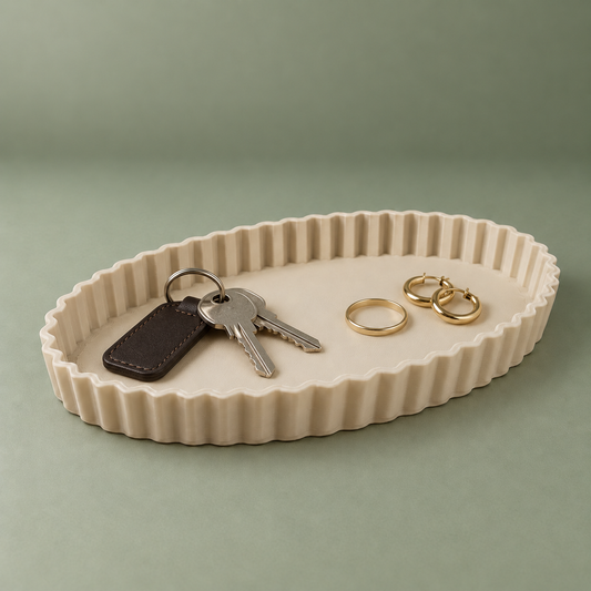 Beige oval ribbed matte PLA tray holding house keys, a leather key tag and gold jewellery on a sage green background